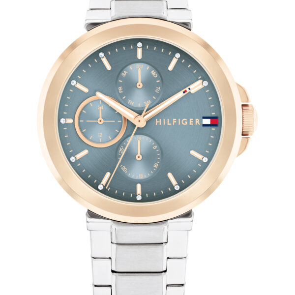 Die Tommy Hilfiger Lori ist eine Armbanduhr mit einem silbernen Metallarmband, einer goldenen Lünette und einem blauen Zifferblatt mit drei Hilfszifferblättern, goldenen Indexen und dem Hilfiger-Logo auf der rechten Seite.