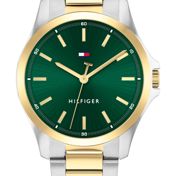 Die Tommy Hilfiger Bruce Armbanduhr verfügt über ein grünes Zifferblatt mit goldenen Indexen, ein gold-silbernes Metallarmband und eine goldene Lünette. Auf dem Zifferblatt sind das Hilfiger-Logo und der Name abgebildet.