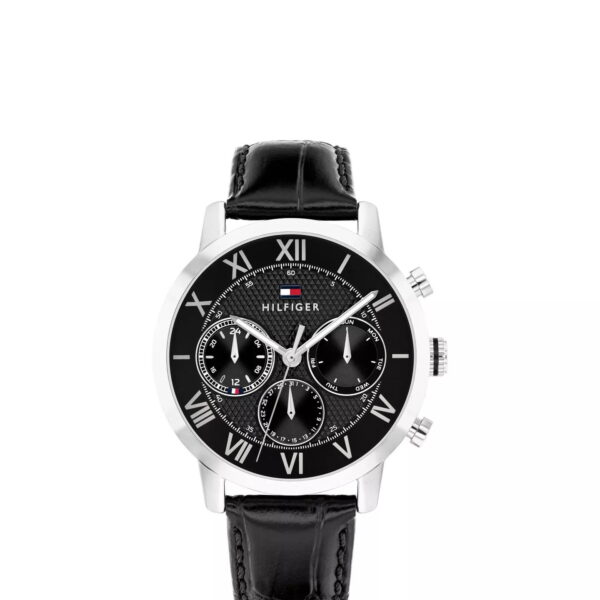 Eine Oxford-Uhr von Tommy Hilfiger mit schwarzem Lederarmband, silbernem Gehäuse, schwarzem Zifferblatt mit römischen Ziffern, drei Hilfszifferblättern und dem Schriftzug „Hilfiger“ unter einem kleinen rot-weiß-blauen Logo.