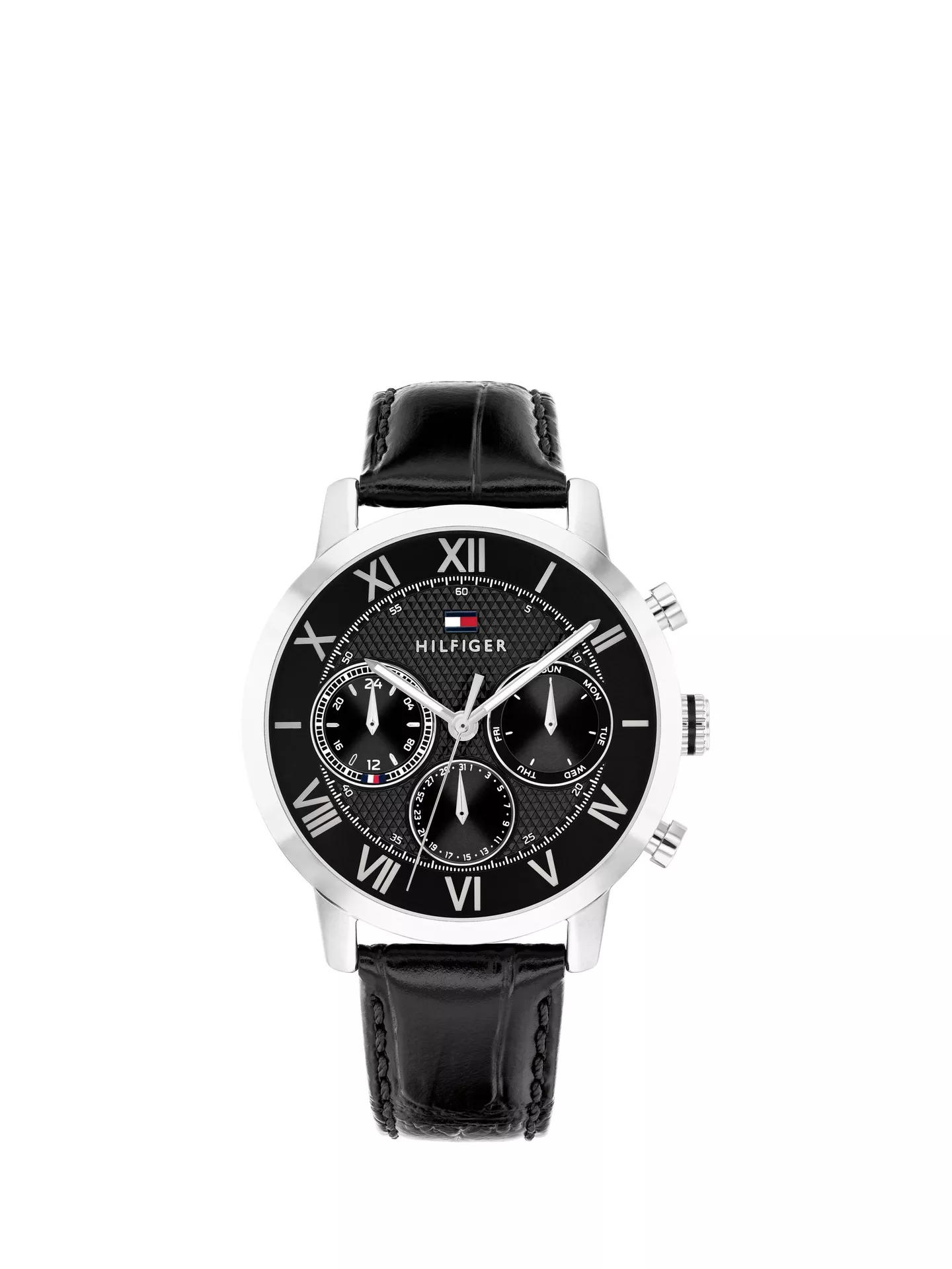 Eine Oxford-Uhr von Tommy Hilfiger mit schwarzem Lederarmband, silbernem Gehäuse, schwarzem Zifferblatt mit römischen Ziffern, drei Hilfszifferblättern und dem Schriftzug „Hilfiger“ unter einem kleinen rot-weiß-blauen Logo.