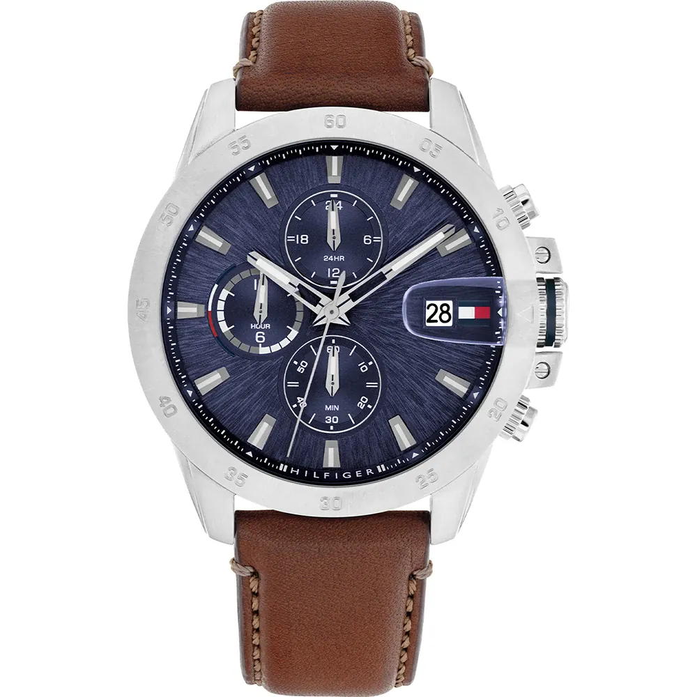 Die Tommy Hilfiger Jameson ist eine silberne Armbanduhr mit einem dunkelblauen Zifferblatt, drei Hilfszifferblättern, einer Datumsanzeige und dem Tommy Hilfiger-Logo bei 3 Uhr, ergänzt durch ein braunes Lederarmband.