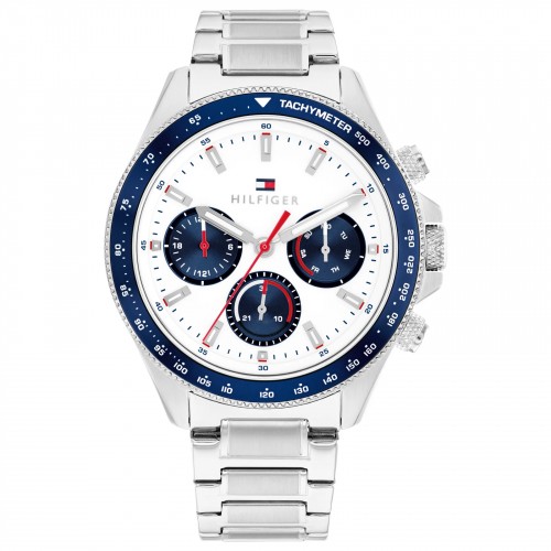 Die Tommy Hilfiger Clark ist eine silberne Chronographenuhr mit weißem Zifferblatt, blauer Lünette und drei blauen Hilfszifferblättern. Sie wird mit einem Metallgliederarmband geliefert und ist mit roten, weißen und blauen Details verziert.