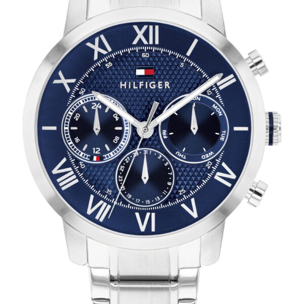 Die Tommy Hilfiger Oxford Armbanduhr verfügt über ein silberfarbenes Metallgliederarmband, ein blaues Zifferblatt mit römischen Ziffern, drei Hilfszifferblätter und das Tommy Hilfiger-Logo direkt unterhalb der 12-Uhr-Position.
