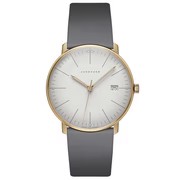 Die Junghans Max Bill Quarz ist eine minimalistische Armbanduhr mit weißem Zifferblatt, goldenem Gehäuse, schlichten Indexen, schlanken Zeigern und einem grauen Lederarmband. Der Markenname „Junghans“ ist auf dem Zifferblatt zu sehen.