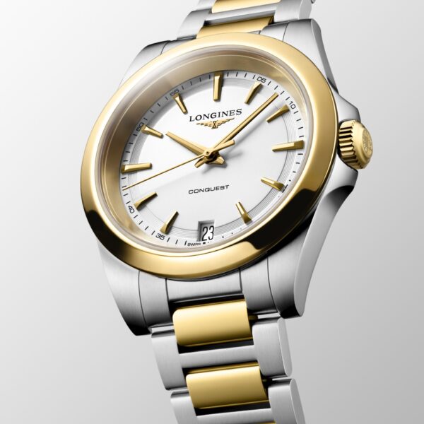Die Armbanduhr „Longines Conquest“ mit einem Gehäuse aus Edelstahl und Gold, einem weißen Zifferblatt, einer goldenen Lünette und Krone sowie einem Datumsfenster bei 6 Uhr wird schräg vor einem hellgrauen Hintergrund präsentiert.