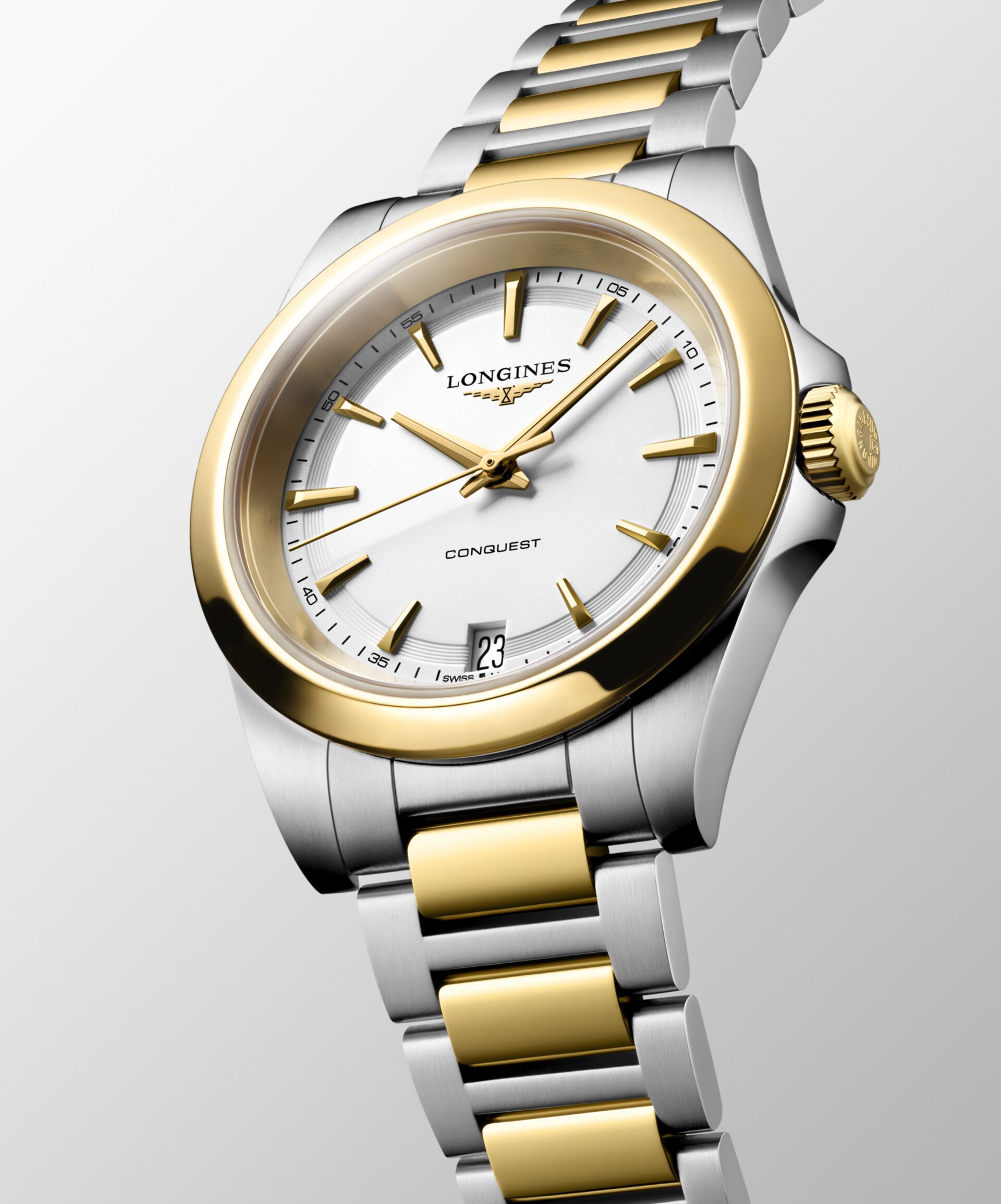Die Armbanduhr „Longines Conquest“ mit einem Gehäuse aus Edelstahl und Gold, einem weißen Zifferblatt, einer goldenen Lünette und Krone sowie einem Datumsfenster bei 6 Uhr wird schräg vor einem hellgrauen Hintergrund präsentiert.