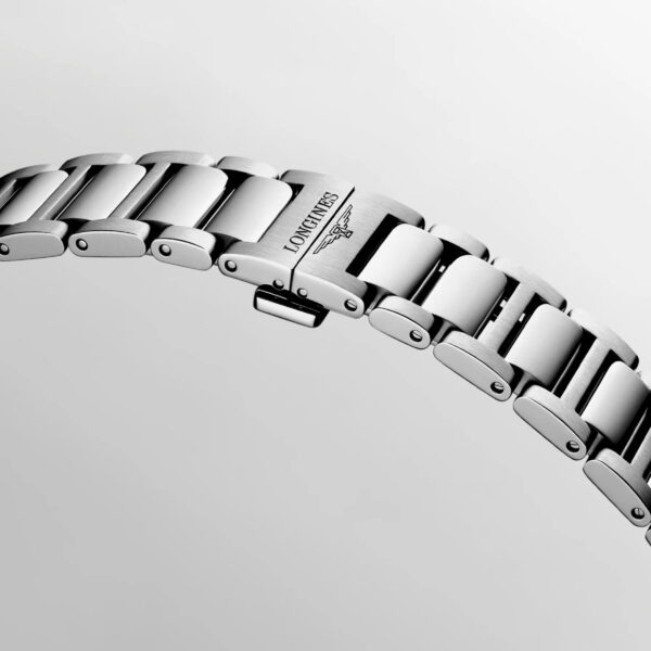 Nahaufnahme eines silberfarbenen Metallarmbands der Longines Conquest-Uhr mit der Gravur „LONGINES“ und einem geflügelten Sanduhr-Logo auf einem der Glieder vor hellgrauem Hintergrund.