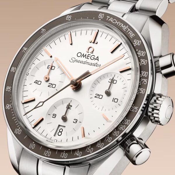 Eine Nahaufnahme der OMEGA Speedmaster 38 Armbanduhr mit weißem Zifferblatt, silbernen Indexen, drei Hilfszifferblättern, einer Tachymeter-Lünette und einem Edelstahlarmband vor beigem Hintergrund.