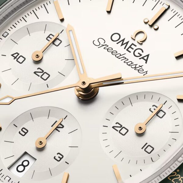 Nahaufnahme des Zifferblatts einer OMEGA Speedmaster 38 mit goldenen Zeigern, drei Hilfszifferblättern, einem Datumsfenster bei 6 Uhr, filigranen Markierungen und dem markanten OMEGA-Logo.
