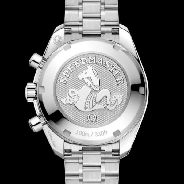 Die Rückseite einer silberfarbenen OMEGA Speedmaster 38 mit strukturiertem, rundem Gehäuseboden, auf dem ein Seepferdchen-Emblem, der Schriftzug „Speedmaster“ sowie die Angabe „100 m / 330 ft“ eingraviert sind, kombiniert mit einem Metallarmband vor schwarzem Hintergrund.