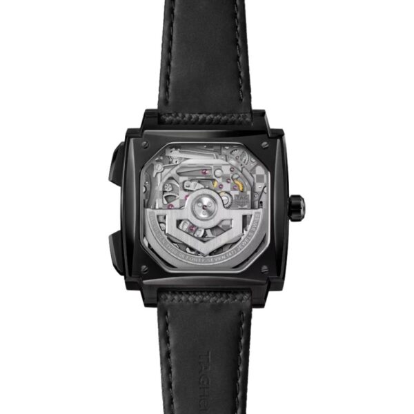 Entdecken Sie die TAG Heuer Monaco Evergraph, eine Uhr mit quadratischem Zifferblatt und schwarzem Lederarmband, deren mechanisches Uhrwerk und freiliegende Zahnräder durch das transparente Zifferblatt sichtbar sind.