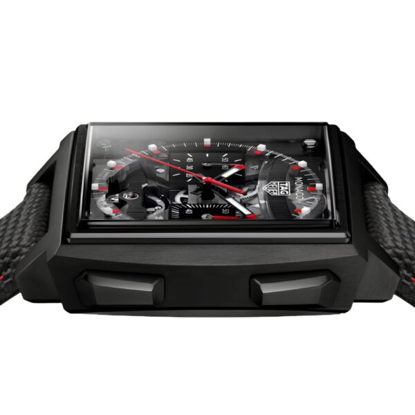 Die TAG Heuer Monaco Evergraph ist eine schwarze, quadratische Uhr mit einem strukturierten schwarzen Armband mit roten Nähten. Ihr detailreich gestaltetes schwarzes Zifferblatt besticht durch rote und weiße Akzente sowie mehrere Hilfszifferblätter. Die Uhr wird von vorne in einem leicht nach oben gerichteten Winkel betrachtet.