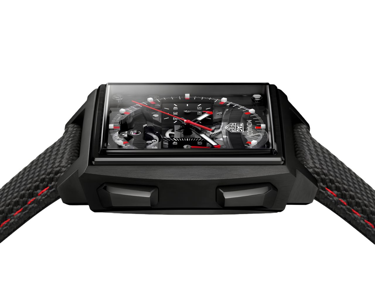 Die TAG Heuer Monaco Evergraph ist eine schwarze, quadratische Uhr mit einem strukturierten schwarzen Armband mit roten Nähten. Ihr detailreich gestaltetes schwarzes Zifferblatt besticht durch rote und weiße Akzente sowie mehrere Hilfszifferblätter. Die Uhr wird von vorne in einem leicht nach oben gerichteten Winkel betrachtet.